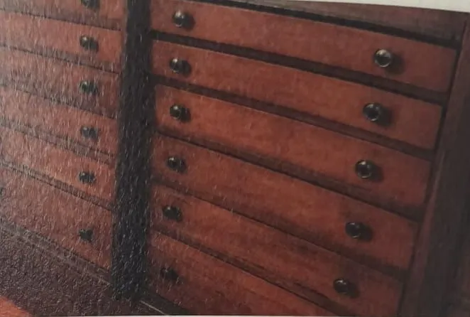 The workshop’s historic chest of drawers: rows of reddish wooden drawers with brass knobs